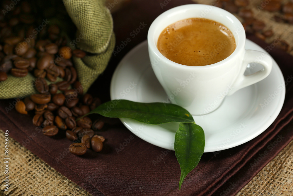 Cup of coffee with beans on table close up