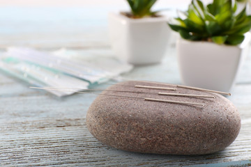 Wall Mural - Acupuncture needles with spa stone on wooden table, closeup