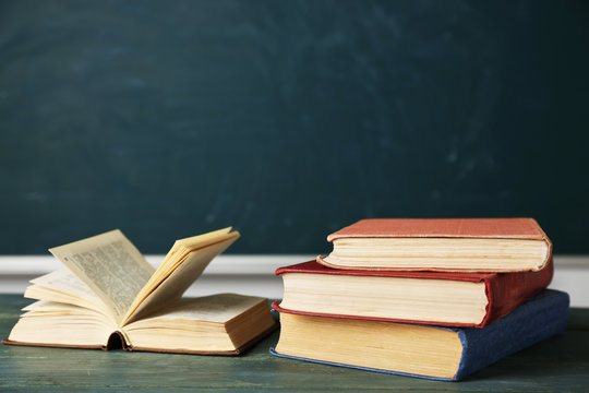 Stack of books on desk, on blackboard background