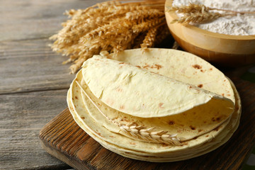 Sticker - Stack of homemade whole wheat flour tortilla on cutting board, on wooden table background