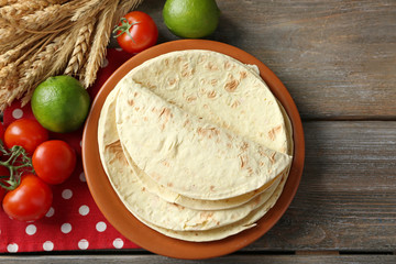 Poster - Stack of homemade whole wheat flour tortilla and vegetables on plate, on wooden table background