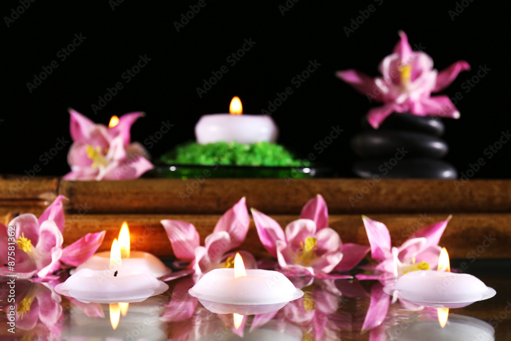 Beautiful spa composition with flowers and candles on black background