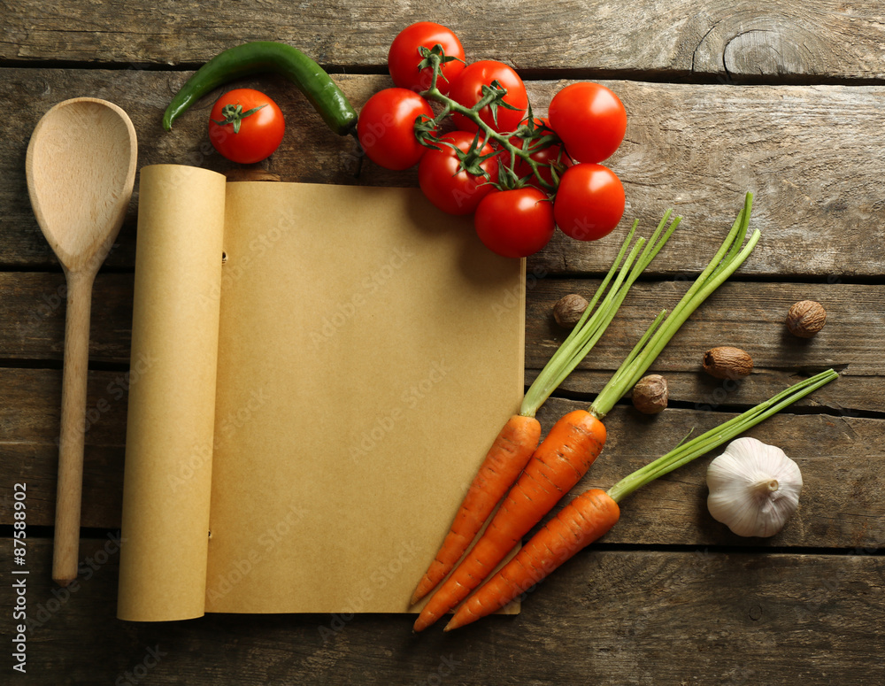 Open recipe book, vegetables and spices on wooden background