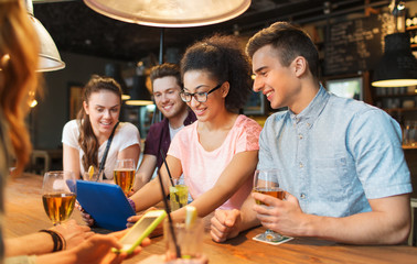 Canvas Print - happy friends with tablet pc and drinks at bar