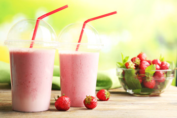 Wall Mural - Glasses of milkshake with strawberries on bright background