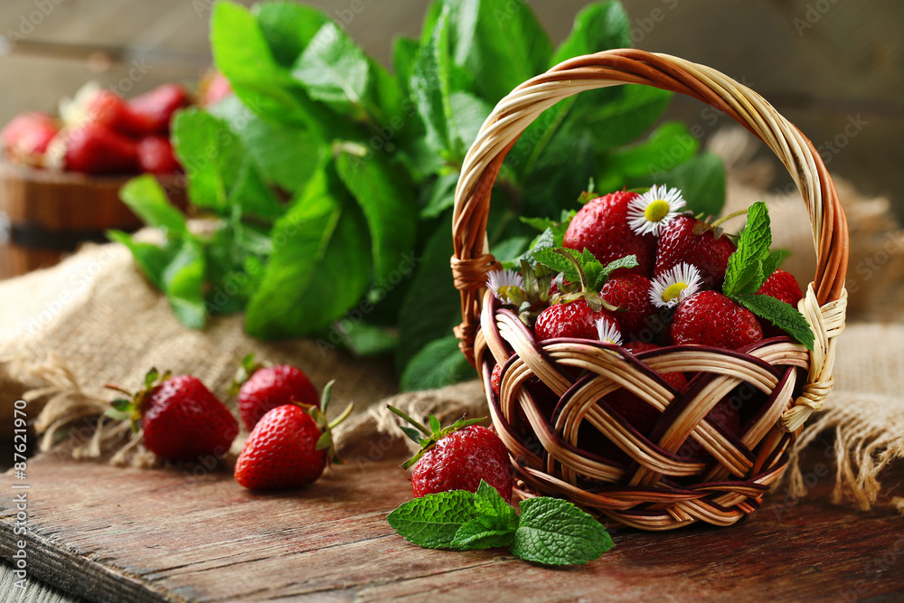 Red ripe strawberries in wicker basket, on wooden background
