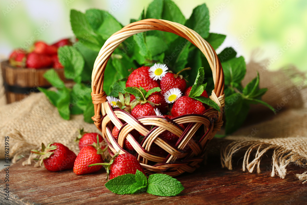 Red ripe strawberries in wicker basket, on bright background