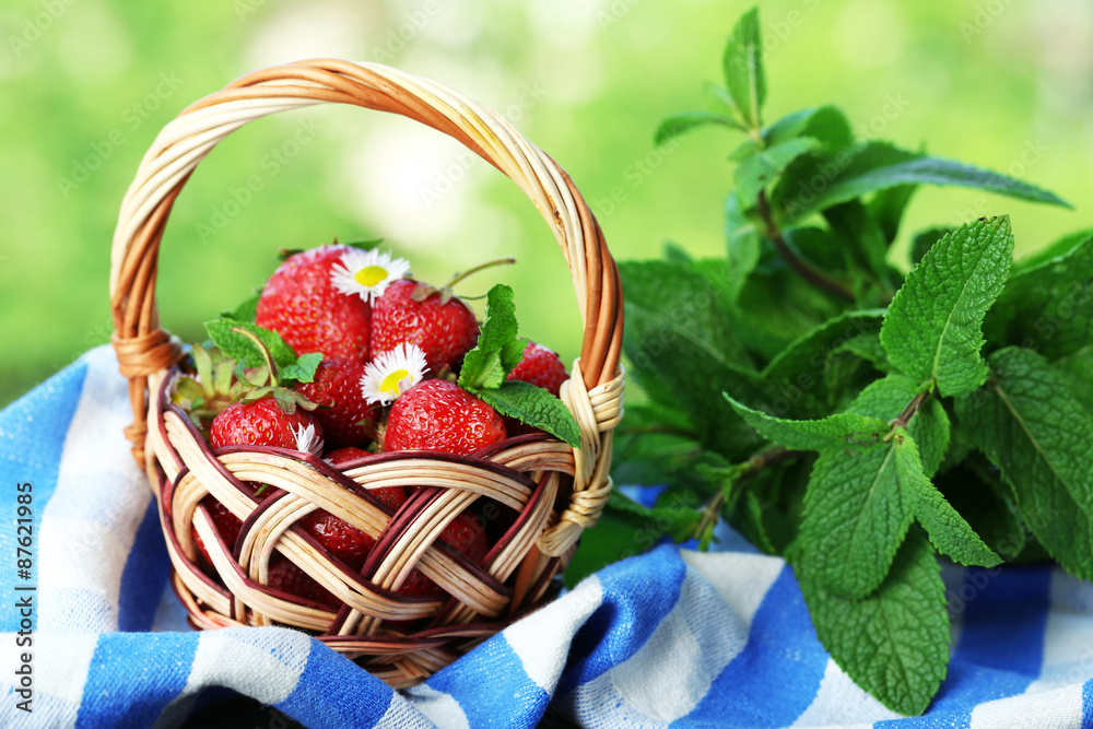 Red ripe strawberries in wicker basket, on bright background