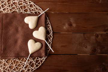 Wall Mural - Chocolate heart shaped candies on sticks with napkin on wooden background