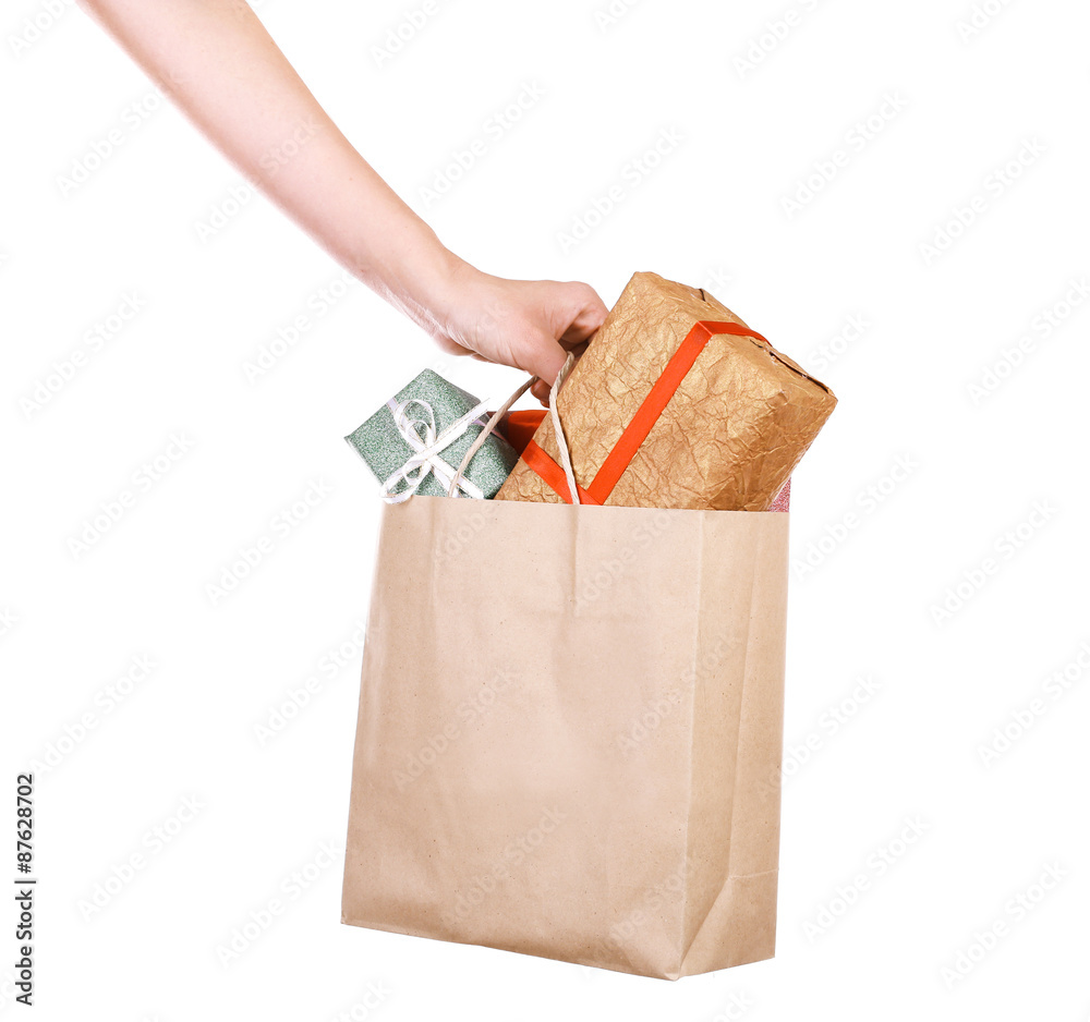 Female hand holding paper bag with present boxes isolated on white