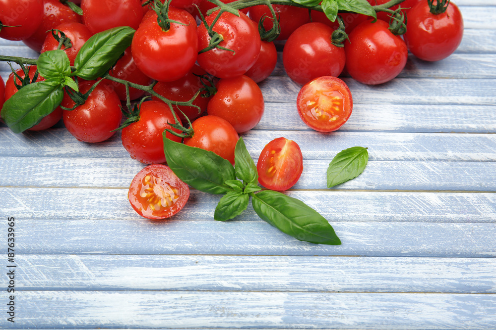 Fresh cherry tomatoes with basil on wooden table close up
