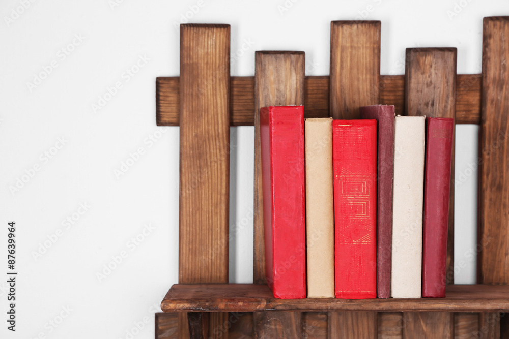 Wooden shelf with books on wall background