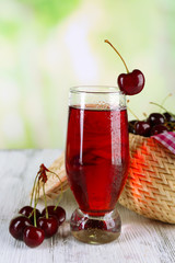 Poster - Glass of cherry juice on wooden table on light blurred background