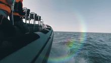 Side View Of Speedboat Racing Along The Coast With A Natural Rainbow Flare On The Side