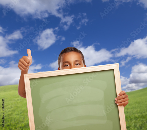 Boy with Thumbs Up in Field Holding Blank Chalk Board