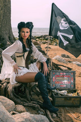 Wall Mural - Beautiful pirate woman sitting near treasure chest on the beach