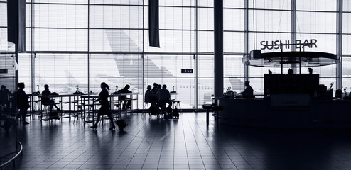 Airport interior with food bar and tourists.