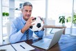 © WavebreakmediaMicro - Happy businessman looking at camera and holding foot ball