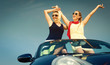 © Kzenon - Zwei Frauen in Cabrio genießen einen Auto Ausflug im Sommer und strecken die Arme aus