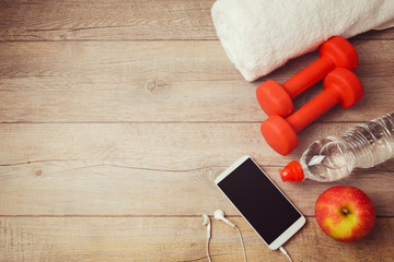 Wall Mural - Fitness background with bottle of water, dumbbells and smartphone. View from above