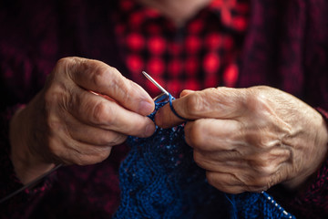 The old woman sits at home and knits garments