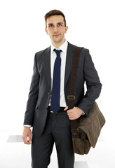 Wall Mural - Man holding suitcase on light background