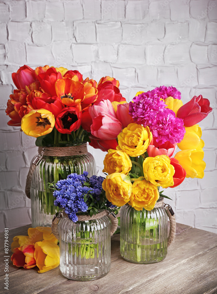 Beautiful flowers in vases on wall background