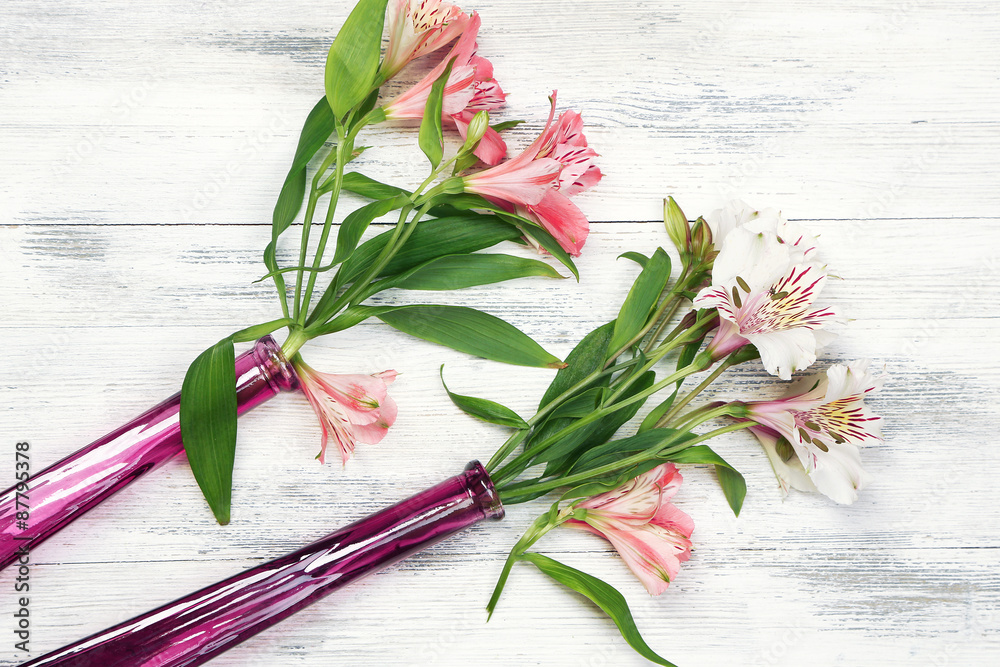 Beautiful alstroemeria in vases on wooden background
