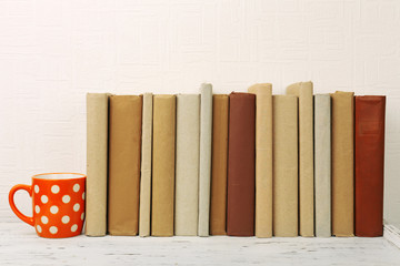 Sticker - Books and cup on wooden shelf on wallpaper background