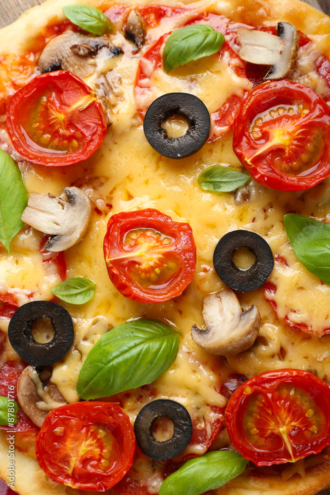 Tasty pizza with vegetables and basil close up