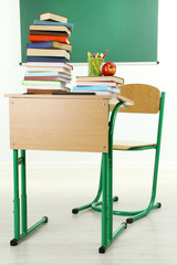 Sticker - Wooden desk with books and chair in class on blackboard background