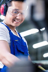 Wall Mural - Asian worker operating metal skip in factory