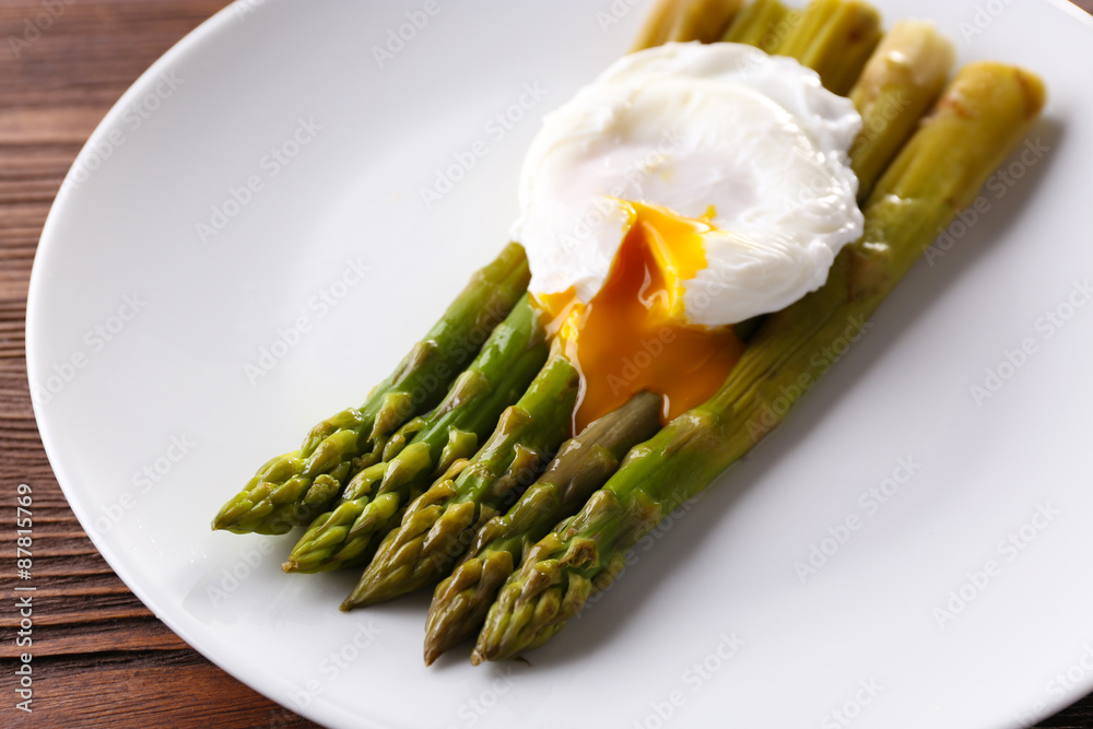 Roasted asparagus with poached egg on plate on table close up