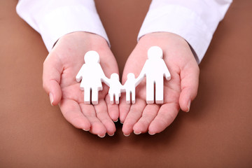 Wall Mural - Female hands holding toy family on color background