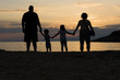 Family on a beach holding hands at sunset