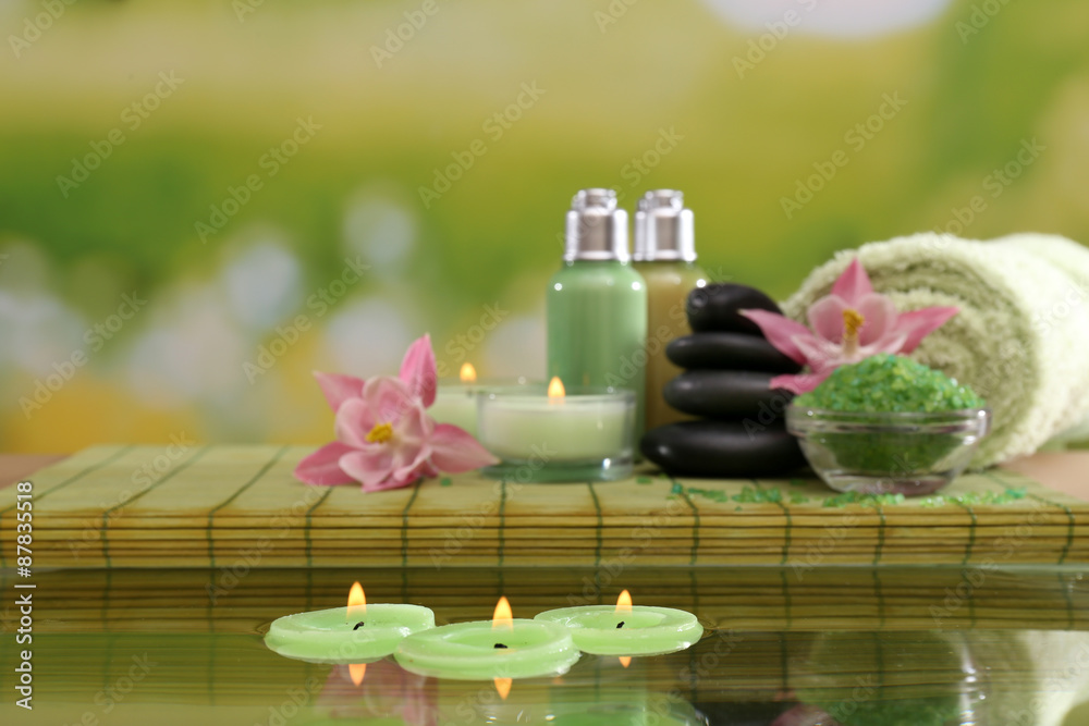 Spa still life with flowers and candlelight on green blurred background