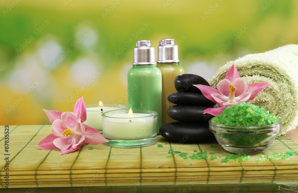 Spa still life with flowers and candlelight on green blurred background