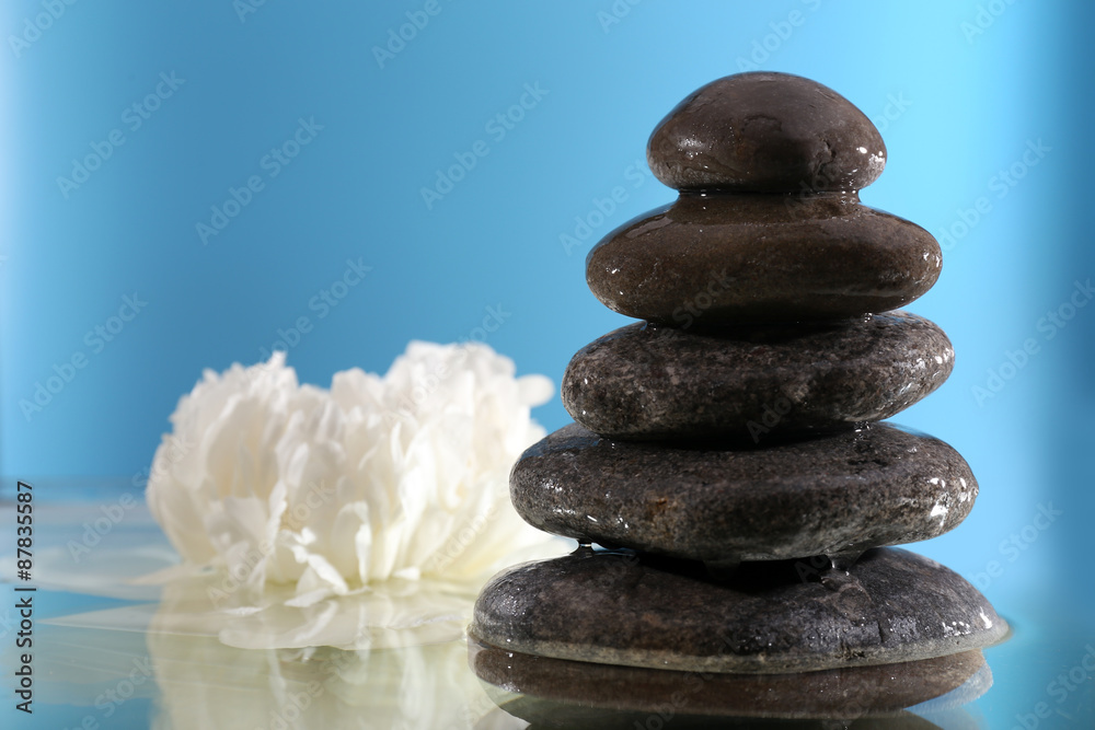 Stack of spa stones with flower on blue background