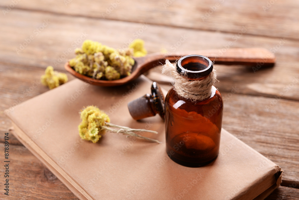 Old book with dry flowers and bottle on table close up