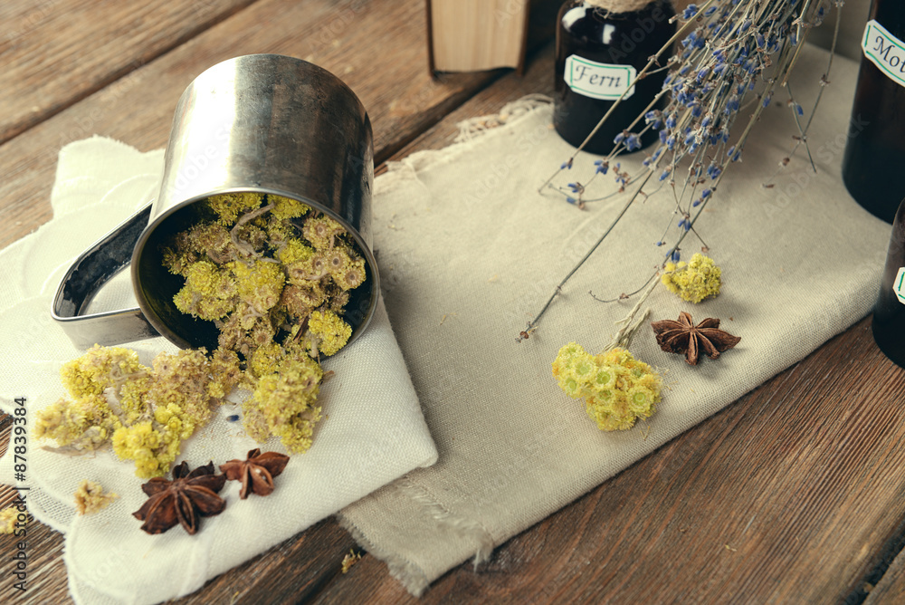 Dried herbs and bottles with tinctures on table close up