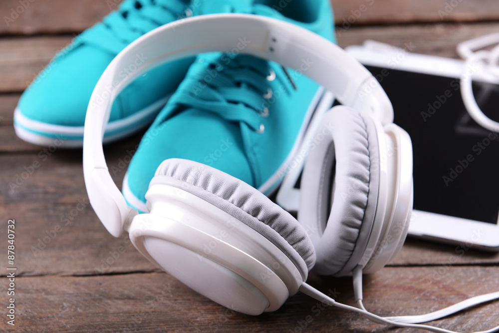 Headphones with sneakers and tablet on wooden background
