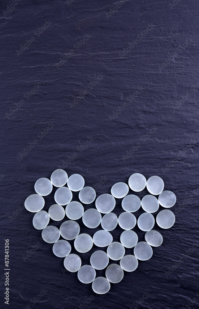 Decorative stones in heart shape on gray background