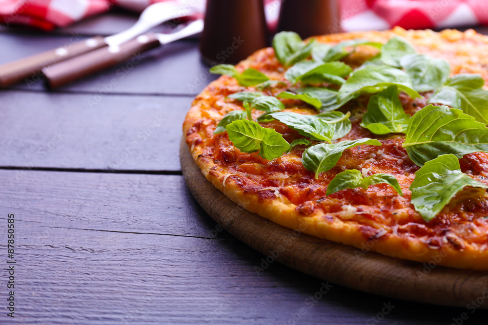 Pizza with basil on wooden table, closeup