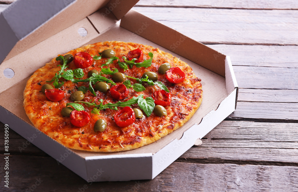 Pizza in box on wooden table, closeup