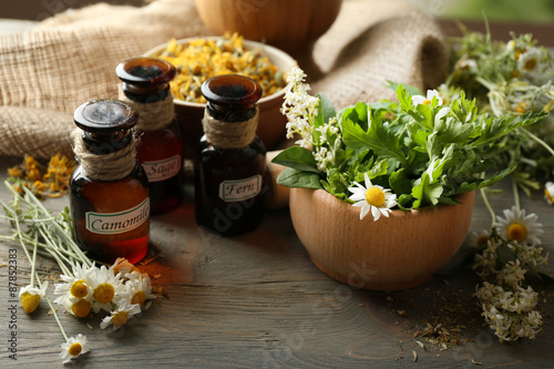 Obraz Dibond Herbs, berries and flowers with mortar, on wooden table background