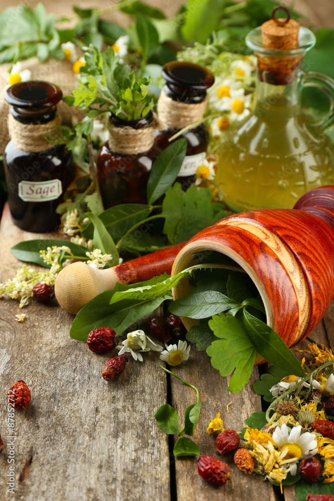 Herbs, berries and flowers with mortar, on wooden table background