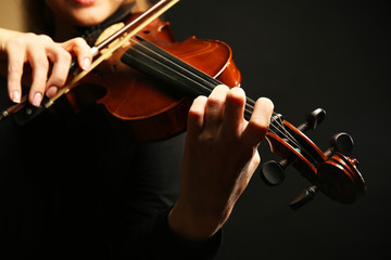 Wall Mural - Violinist playing violin on dark background