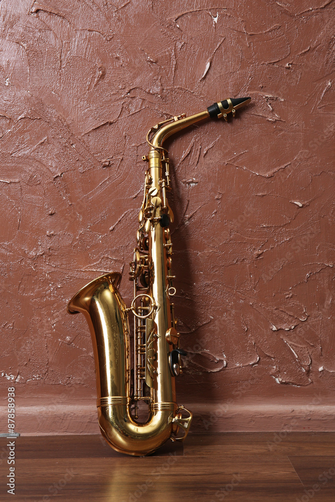 Golden saxophone on brown wall background