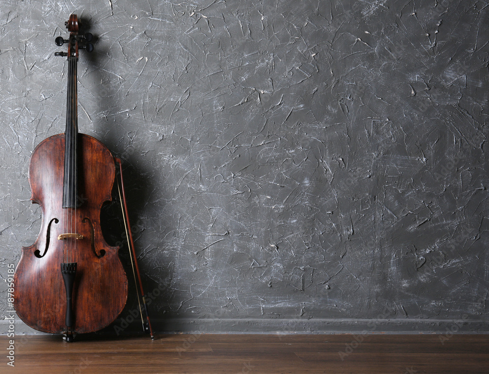 Classical cello and bow on gray wall background - obrazy, fototapety, plakaty 