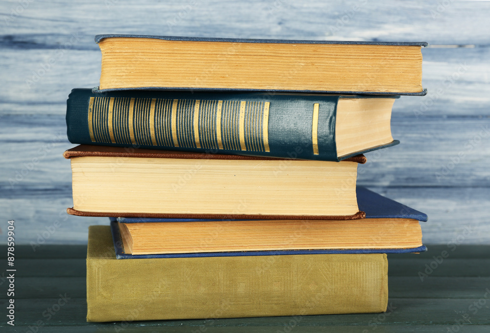 Stack of books on wooden table on blue wooden wall background